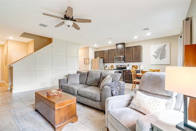 living area with a ceiling fan, recessed lighting, visible vents, and a decorative wall