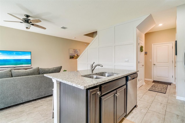 kitchen featuring light stone counters, visible vents, open floor plan, a sink, and dishwasher