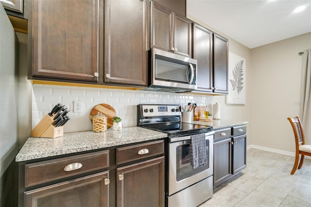 kitchen with baseboards, light stone counters, stainless steel appliances, dark brown cabinets, and backsplash