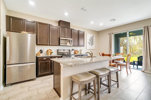 kitchen featuring visible vents, appliances with stainless steel finishes, a kitchen breakfast bar, and a sink