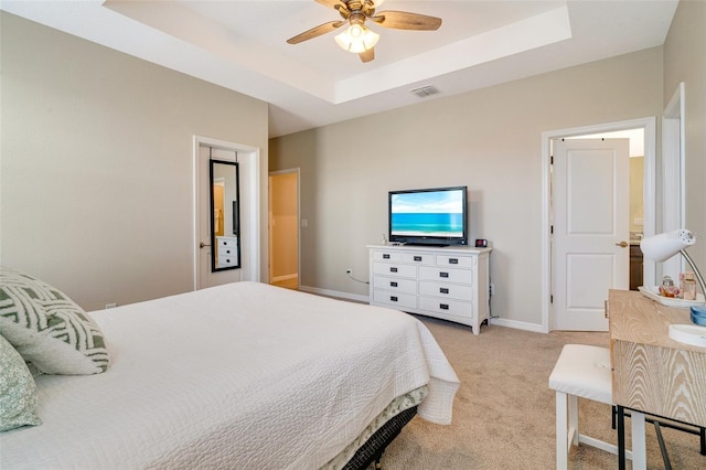 bedroom with light carpet, a tray ceiling, visible vents, and baseboards