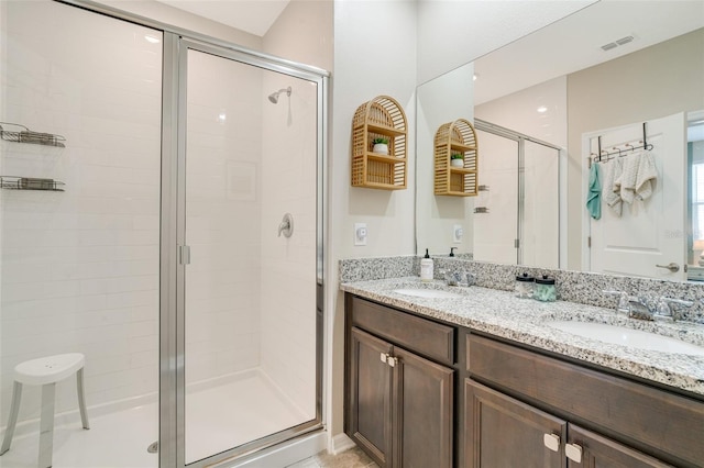 bathroom featuring double vanity, a stall shower, a sink, and visible vents