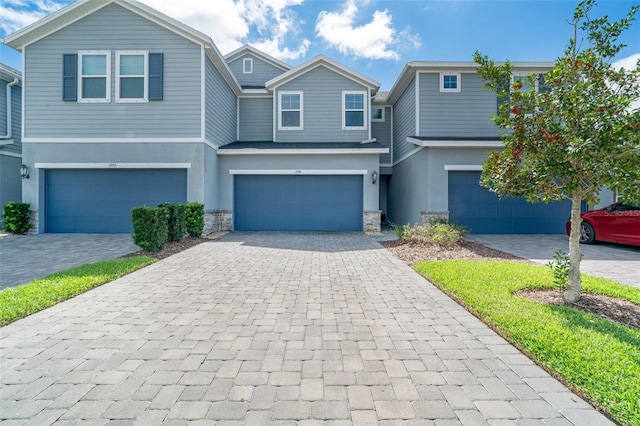 view of front facade featuring decorative driveway, an attached garage, and stucco siding