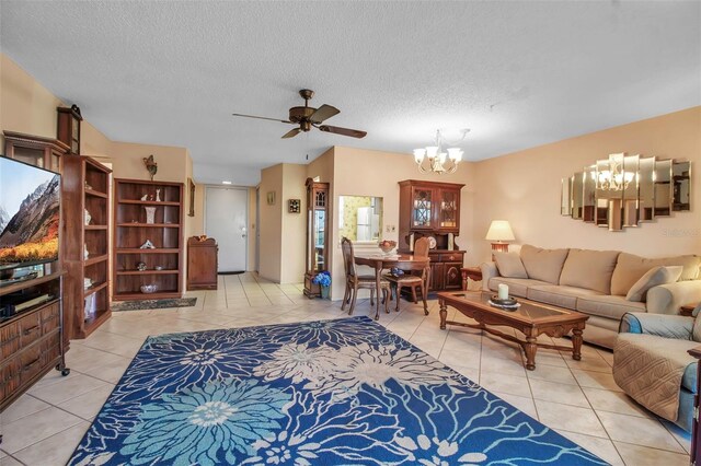 living room featuring ceiling fan with notable chandelier, a textured ceiling, and light tile patterned flooring