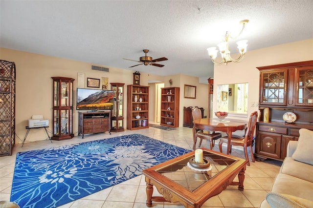 living room with ceiling fan with notable chandelier, visible vents, a textured ceiling, and light tile patterned flooring