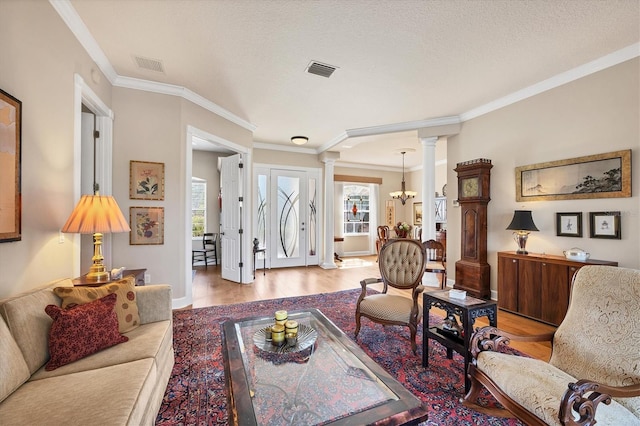 living area with a healthy amount of sunlight, visible vents, ornate columns, and wood finished floors