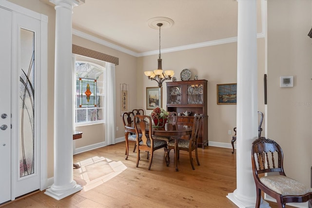 dining space with a chandelier, light wood finished floors, ornamental molding, and decorative columns