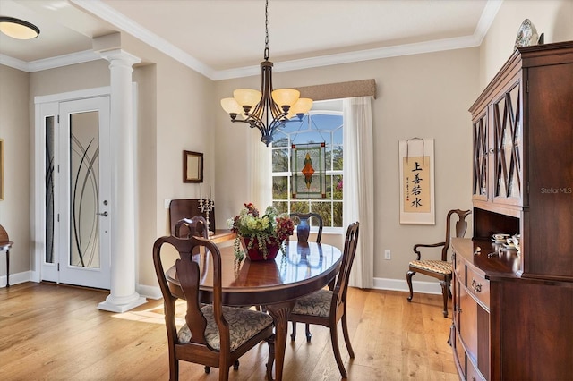 dining room featuring light wood-type flooring, crown molding, and ornate columns