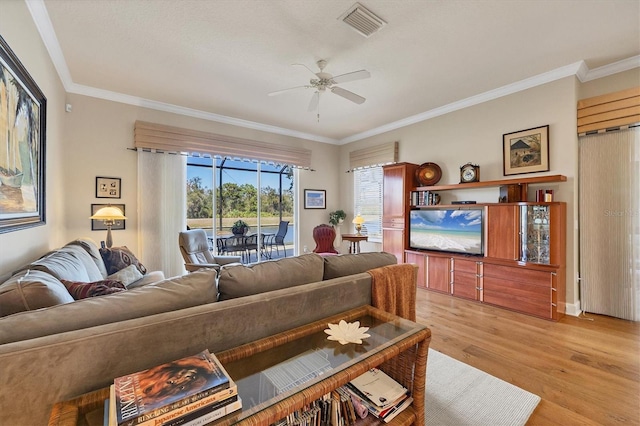 living area with visible vents, crown molding, light wood finished floors, and ceiling fan