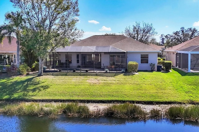 rear view of house featuring a water view, stucco siding, a lanai, and a yard