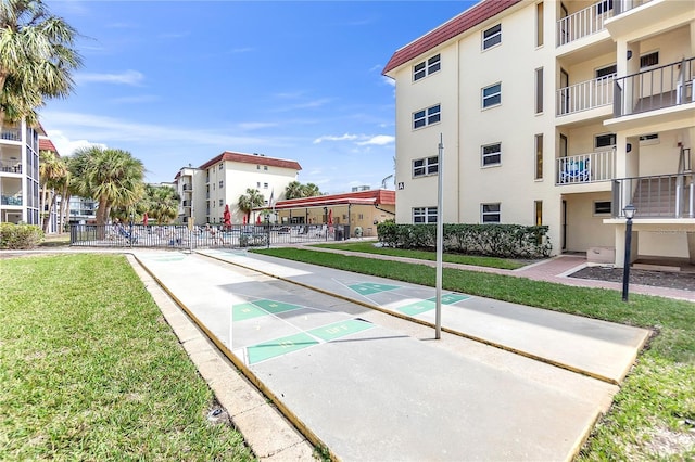 view of property's community with a yard, fence, and shuffleboard