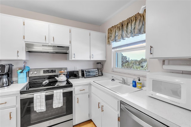 kitchen with white cabinets, appliances with stainless steel finishes, light countertops, under cabinet range hood, and a sink