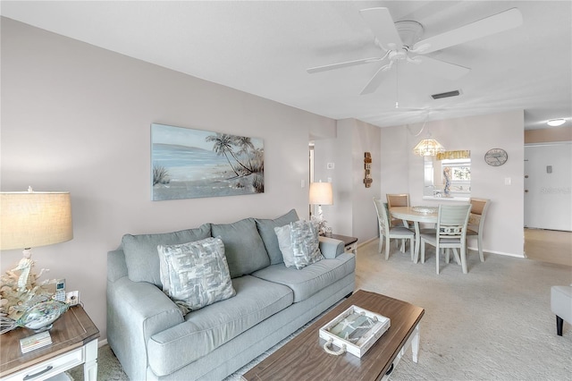 living area featuring light carpet, baseboards, visible vents, and a ceiling fan