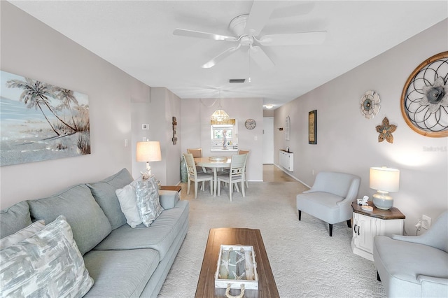 living area with a ceiling fan, visible vents, and light colored carpet