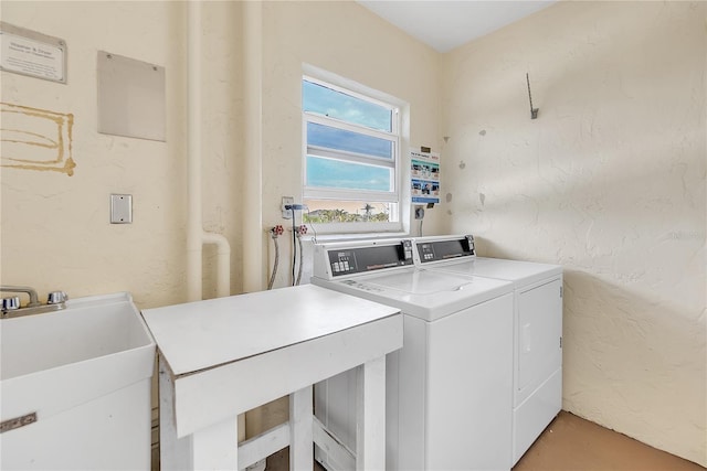 community laundry room with a textured wall, separate washer and dryer, and a sink