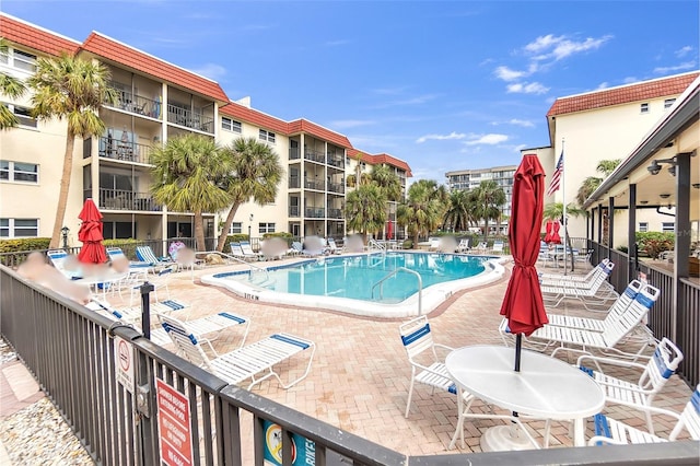 community pool with a patio area and fence