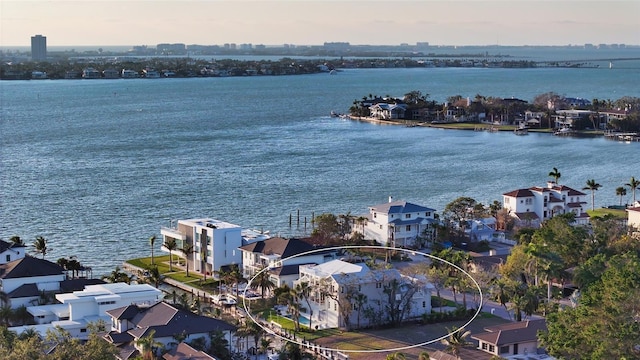 aerial view at dusk featuring a water view and a residential view