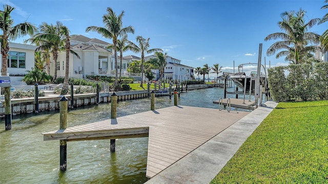 dock area with a water view, boat lift, a residential view, and a lawn