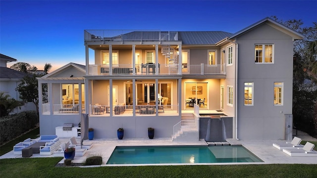 rear view of property with a patio area, a balcony, and an outdoor pool