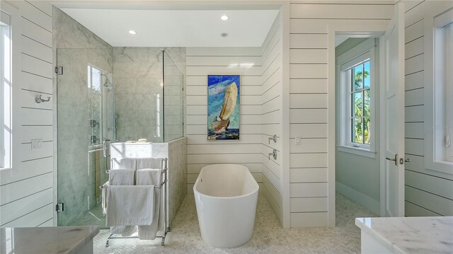 bathroom featuring a freestanding bath, wooden walls, and a shower stall