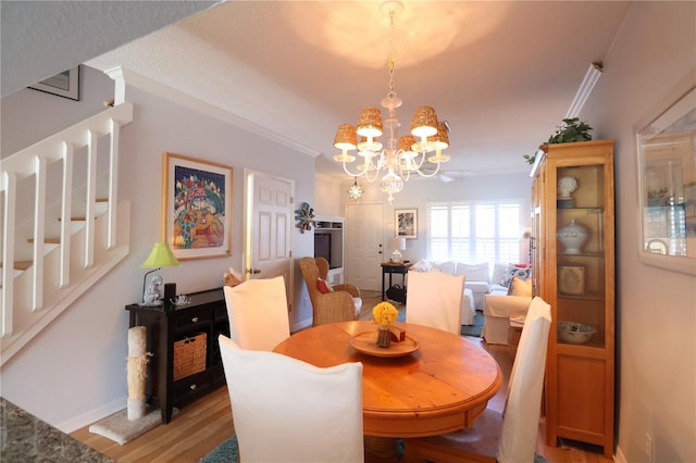 dining room featuring ornamental molding, a notable chandelier, light wood-style flooring, and baseboards