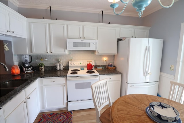 kitchen with white appliances, white cabinets, and a sink