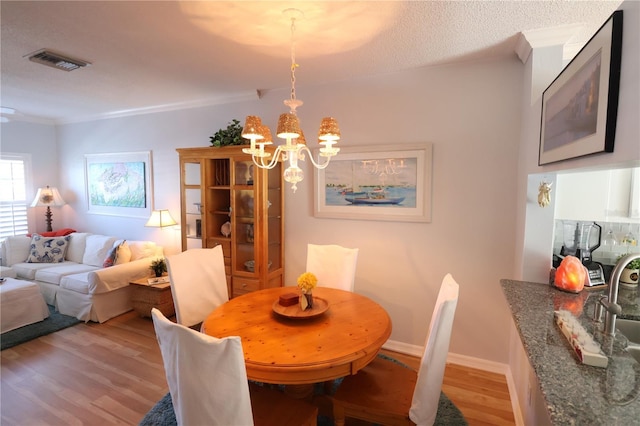 dining space with visible vents, baseboards, light wood-style flooring, crown molding, and a notable chandelier