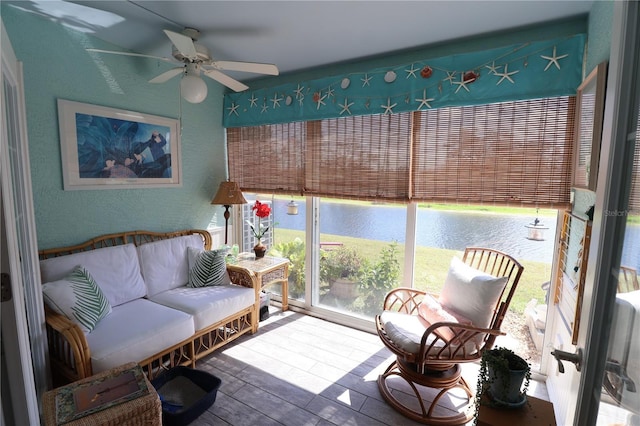 sunroom / solarium featuring a water view and a ceiling fan