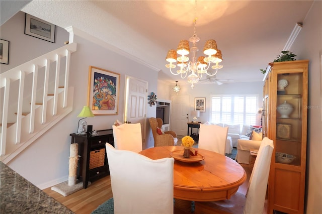 dining room with light wood-style floors, crown molding, a notable chandelier, and baseboards