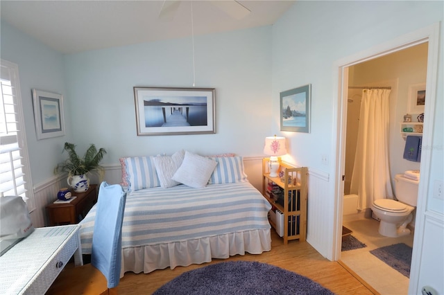 bedroom featuring ensuite bathroom, light wood finished floors, and wainscoting