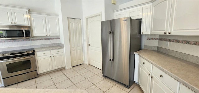 kitchen featuring light tile patterned floors, stainless steel appliances, light countertops, backsplash, and white cabinetry