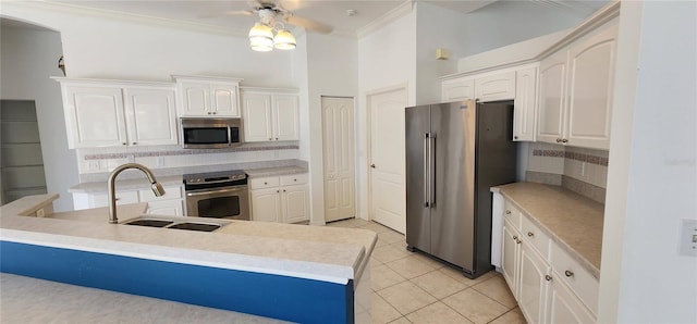 kitchen with white cabinets, a sink, stainless steel appliances, crown molding, and backsplash