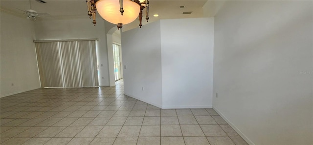 empty room featuring arched walkways, light tile patterned flooring, visible vents, and baseboards