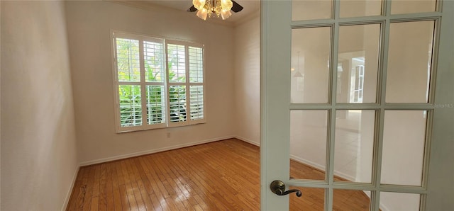 empty room featuring hardwood / wood-style flooring, baseboards, and crown molding