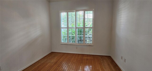 spare room featuring hardwood / wood-style flooring and baseboards