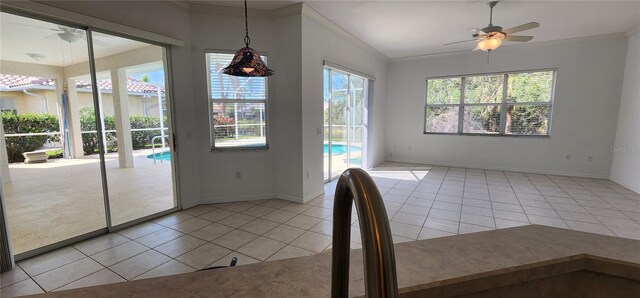 unfurnished dining area with a ceiling fan, crown molding, plenty of natural light, and tile patterned floors