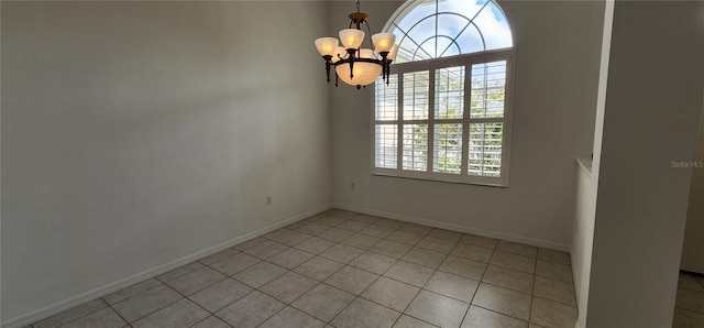 empty room with light tile patterned floors, baseboards, and a notable chandelier