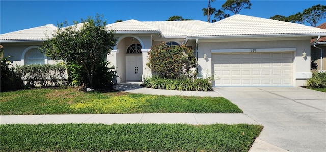 single story home featuring a garage, concrete driveway, stucco siding, a tile roof, and a front yard