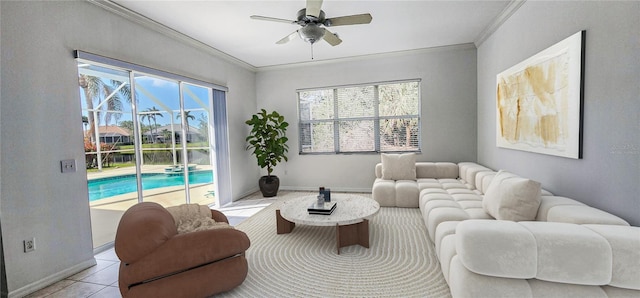 living room with light tile patterned flooring, crown molding, baseboards, and a ceiling fan