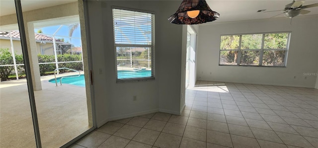 unfurnished dining area featuring tile patterned floors, baseboards, and a ceiling fan
