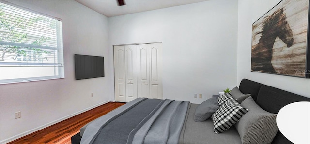 bedroom with baseboards, wood finished floors, and a closet