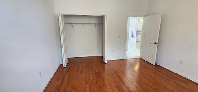 unfurnished bedroom featuring a closet, baseboards, and wood finished floors