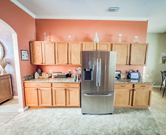 kitchen featuring stainless steel fridge, arched walkways, light stone countertops, crown molding, and light brown cabinetry