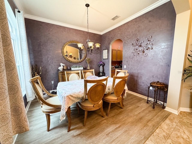 dining space with arched walkways, visible vents, crown molding, and light wood-style flooring