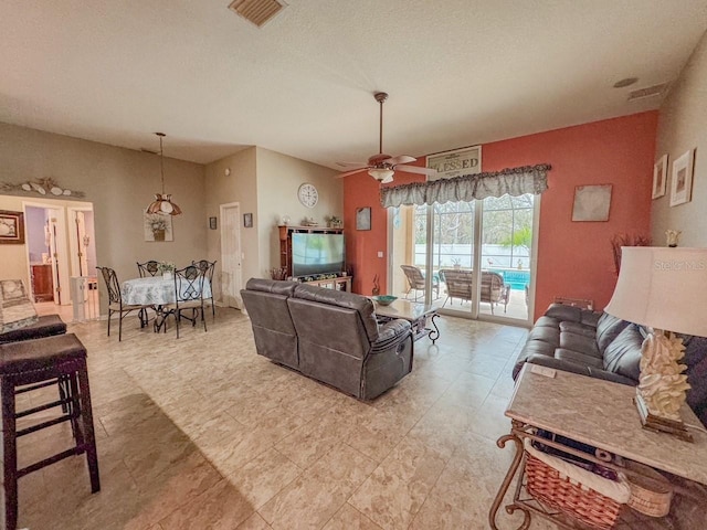 living room with ceiling fan, visible vents, and a textured ceiling