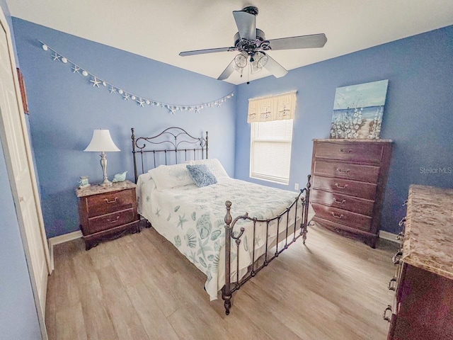 bedroom with a ceiling fan, baseboards, and light wood finished floors