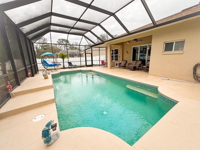 outdoor pool with a ceiling fan, a patio area, glass enclosure, and an outdoor hangout area