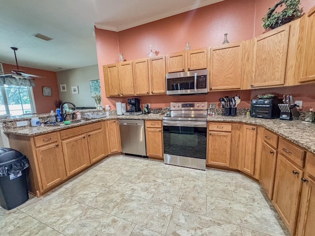 kitchen featuring stainless steel appliances, a sink, a peninsula, and light stone countertops