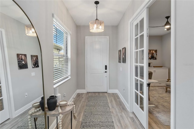 foyer with a chandelier, light wood-type flooring, french doors, and baseboards