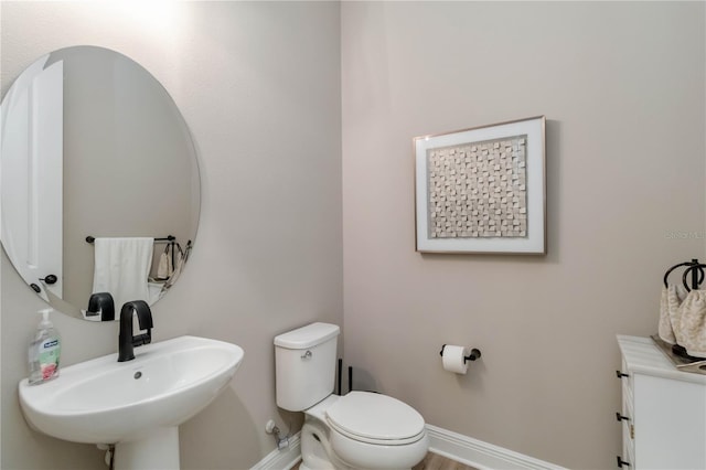 half bath with a sink, toilet, and baseboards